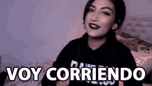 a woman sitting on a bed with the words voy corriendo written on the bottom