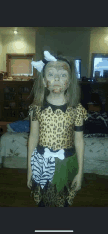 a little girl in a leopard print costume with face paint on