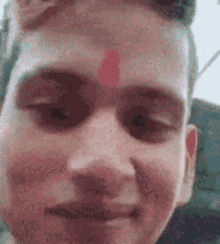 a close up of a young man 's face with a red circle on his forehead .