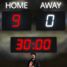 a man stands in front of a scoreboard that says home 90 away 0