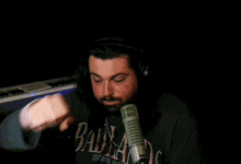 a man wearing a blue teddy fresh sweatshirt is sitting in front of a microphone .