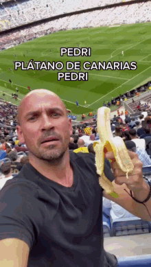 a bald man is holding a banana in front of a soccer field with the words pedri platano de canarias pedri