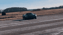 a black sports car is driving on a runway