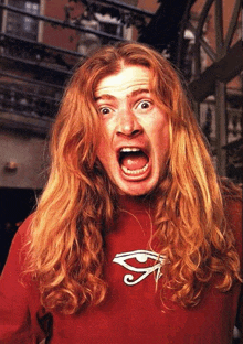 a man with long red hair wearing a red shirt with an eye on it