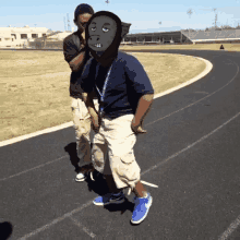 a boy wearing a gorilla mask is walking on a track