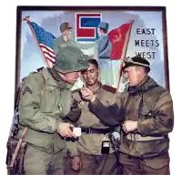 a group of soldiers standing in front of a poster that says east meets west