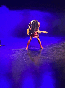 a woman in a red and white dress is playing a guitar on a stage