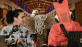 a man in a fox costume talks to a woman in front of a hay bale with a sign that says ranch