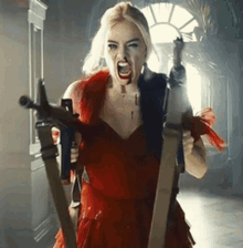 a woman in a red dress is holding two guns in a hallway