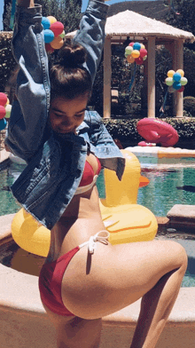 a woman in a red bikini is standing next to a yellow rubber duck