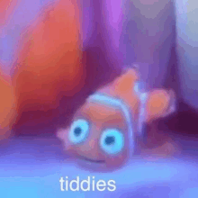 a clown fish from the movie finding nemo is laying on its back with the words tiddies written on it .