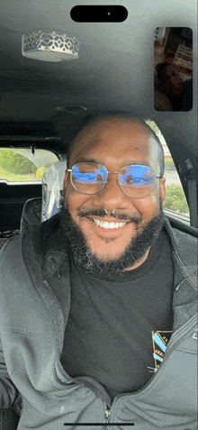 a man with glasses and a nose ring smiles while sitting in a car