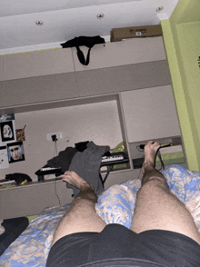 a man laying on a bed with his legs crossed and a box on the ceiling that says braun on it