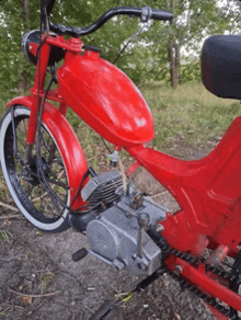 a red motorcycle with a white tire is parked in a field