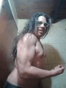 a shirtless man with long hair wearing glasses