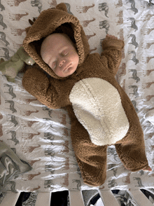 a baby wearing a teddy bear costume is sleeping on a blanket with giraffes on it