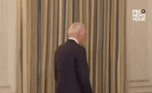 a man in a suit and tie is standing in front of a curtain in a room .