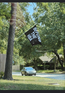 a car is driving down a street with a black flag that says defend the hook