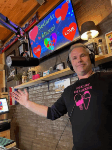 a man wearing headphones stands in front of a screen that says bedankt marcel