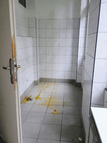 a dirty bathroom with white tiles and a yellow liquid on the floor