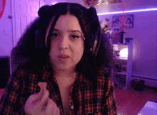 a woman wearing headphones and a plaid shirt holds a piece of food