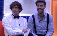 two men wearing suspenders and bow ties are sitting next to each other and smiling