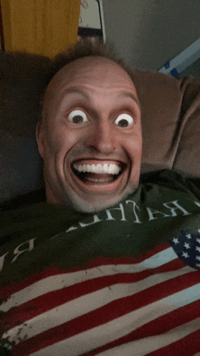 a man laying on a couch wearing an american flag shirt