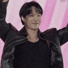 a man wearing a black leather jacket and a black tank top with his arms in the air