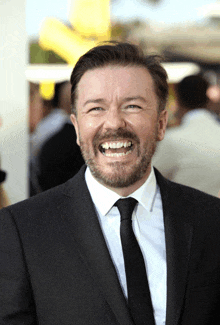 a man with a beard wearing a suit and tie smiles for the camera