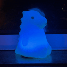 a blue light in the shape of a dinosaur is on a table