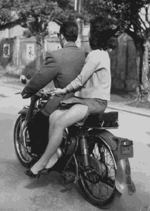 a black and white photo of a man and a woman on a motorcycle with a license plate that says ' sd '