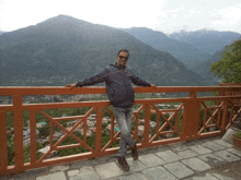 a man stands on a balcony overlooking mountains