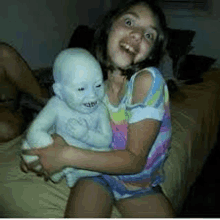 a little girl is sitting on a bed holding a stuffed baby .