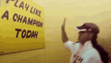 a man giving a high five in front of a sign that says " play like a champion today "