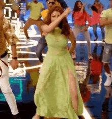 a woman in a green dress is dancing in front of a group of people on a stage .