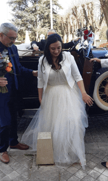 a woman in a white dress is standing next to a stone block