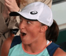 a woman wearing a white hat and a blue tank top is making a surprised face .