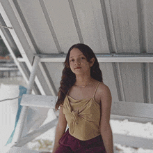 a young girl wearing a tan top and maroon shorts