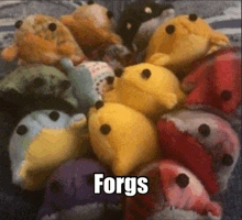 a bunch of stuffed animals are sitting on a bed with the word forgs written on the bottom .