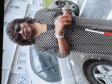 a woman in a black and white polka dot dress holds a white cane