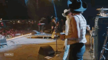 a man in a cowboy hat is playing a guitar in front of a crowd with stagecoach written on the bottom