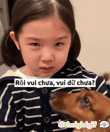 a little girl is holding a dog with a caption that says roi vui chua vui dữ chua