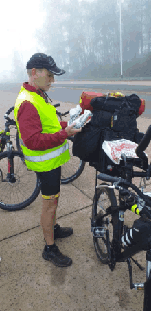 a man wearing a yellow vest is standing next to a bike