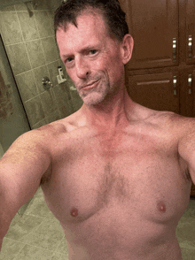 a shirtless man taking a picture of himself in a bathroom