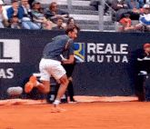 a man is running on a tennis court in front of a wall that has reale mutua written on it