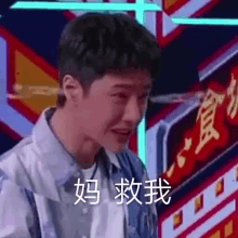 a young man is making a funny face in front of a neon sign in chinese .