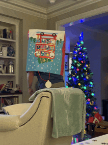 a man is standing in front of a christmas tree with a box on his head that has a bus on it