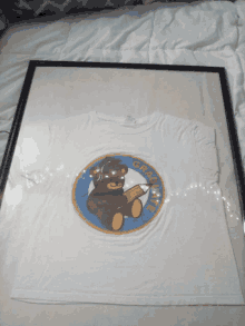 a framed t-shirt with a teddy bear reading a book and the word gratitude on it