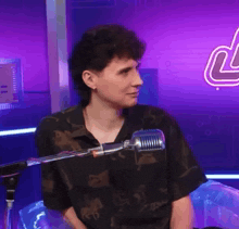 a man is sitting in front of a microphone in a room with a purple background .