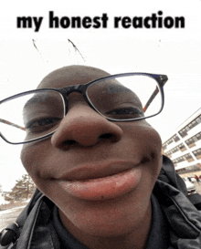 a man wearing glasses is smiling with the words " my honest reaction " behind him